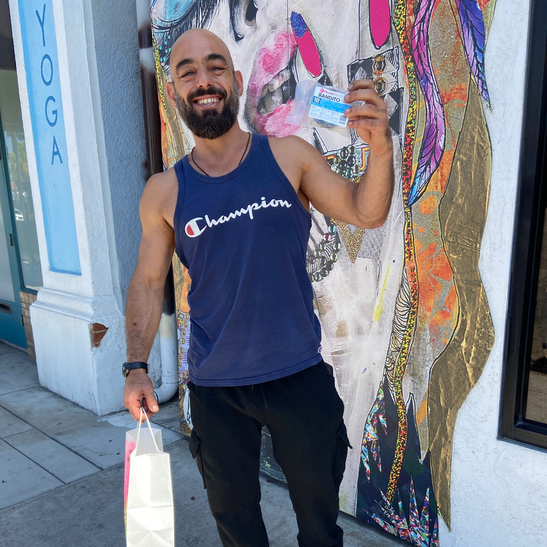 Bandito smiling man with beard holds up bandito paleo dessert in front of san diego store.