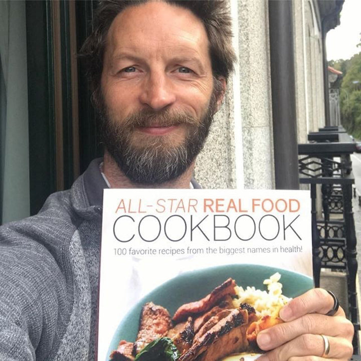 Happy reader holding the All Star Real Food Cookbook in Spain