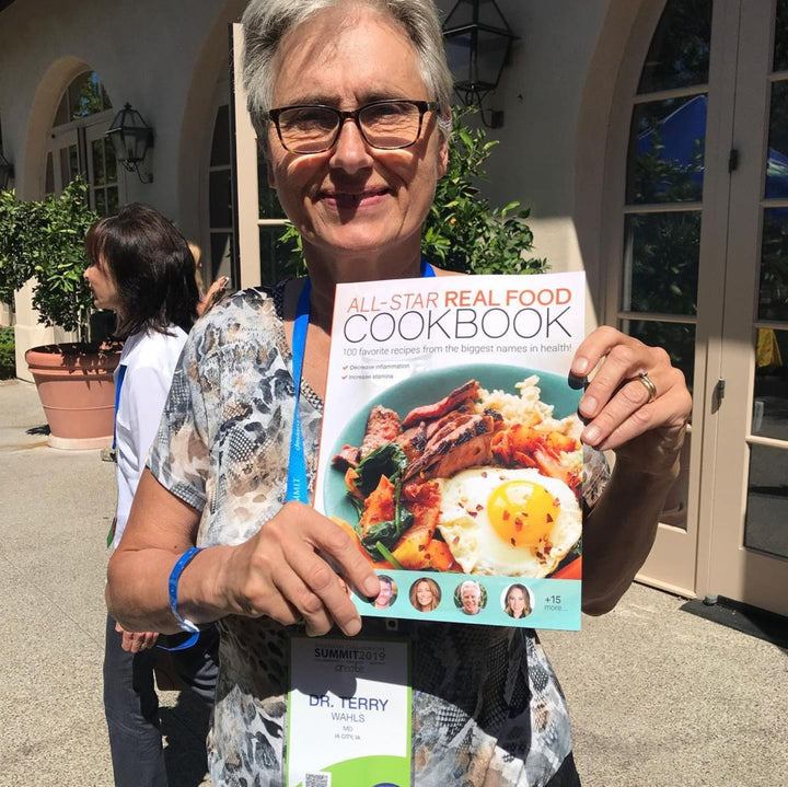Dr. Terry Wahls holding up the All Star Real Food Cookbook