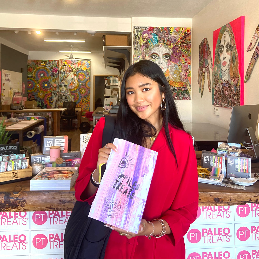 Baller bread smiling woman holds bag of paleo treats.