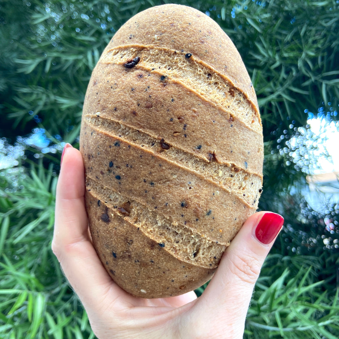 Baller bread womans hand holds up loaf of vegan bread.