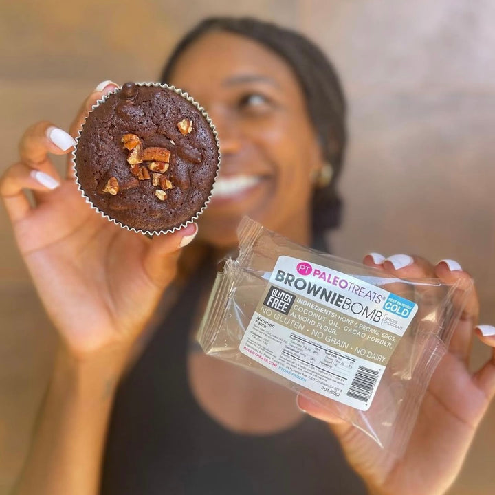 Brownie bomb happy woman holds up gluten free brownie with ingredients.