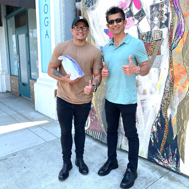 Cacao now two men in front of adams ave store smiling with paleo chocolate in a bag.