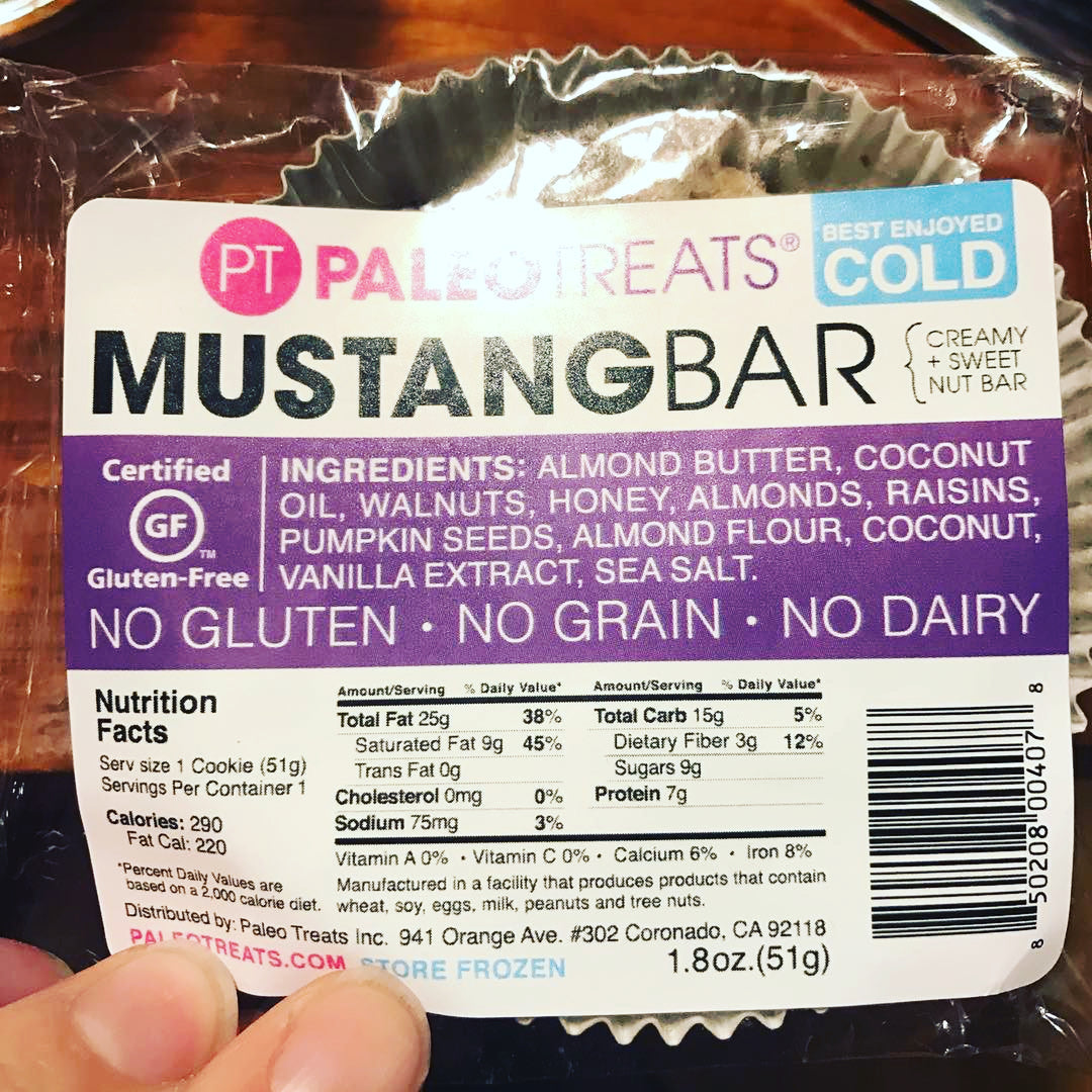 Hand holding paleo treats mustang bar shiny reflection off packaging.
