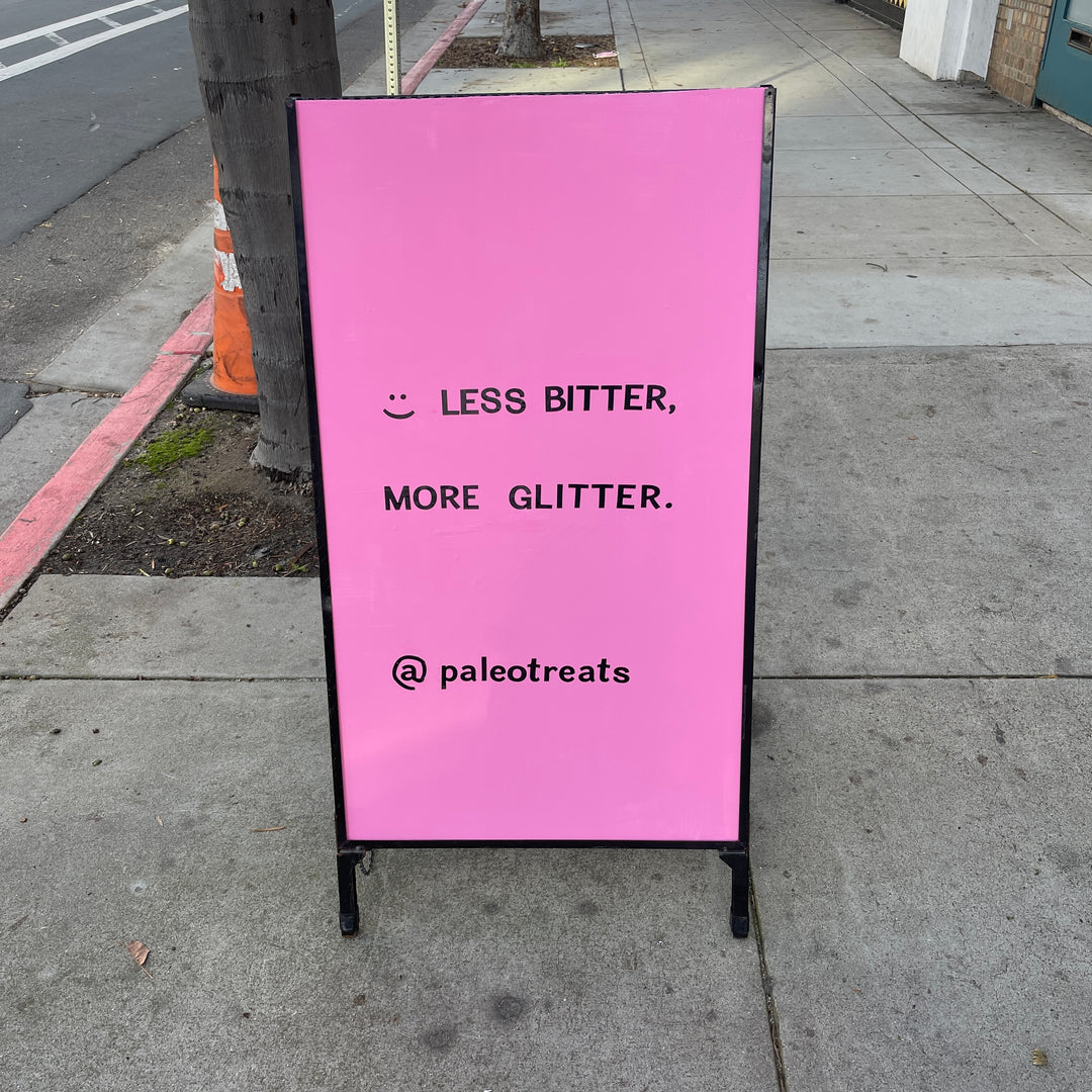 Less bitter more glitter sign outside of paleo treats shop.
