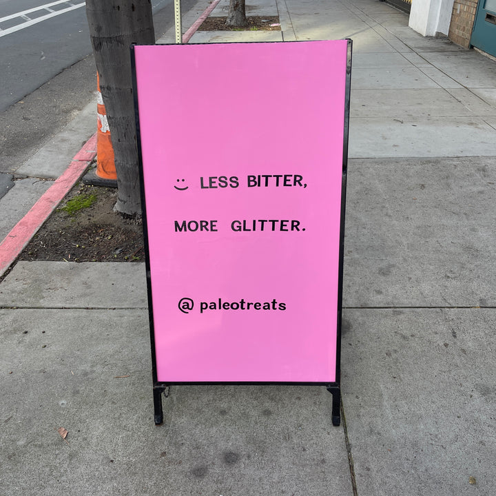 Less bitter more glitter sign outside of paleo treats shop.