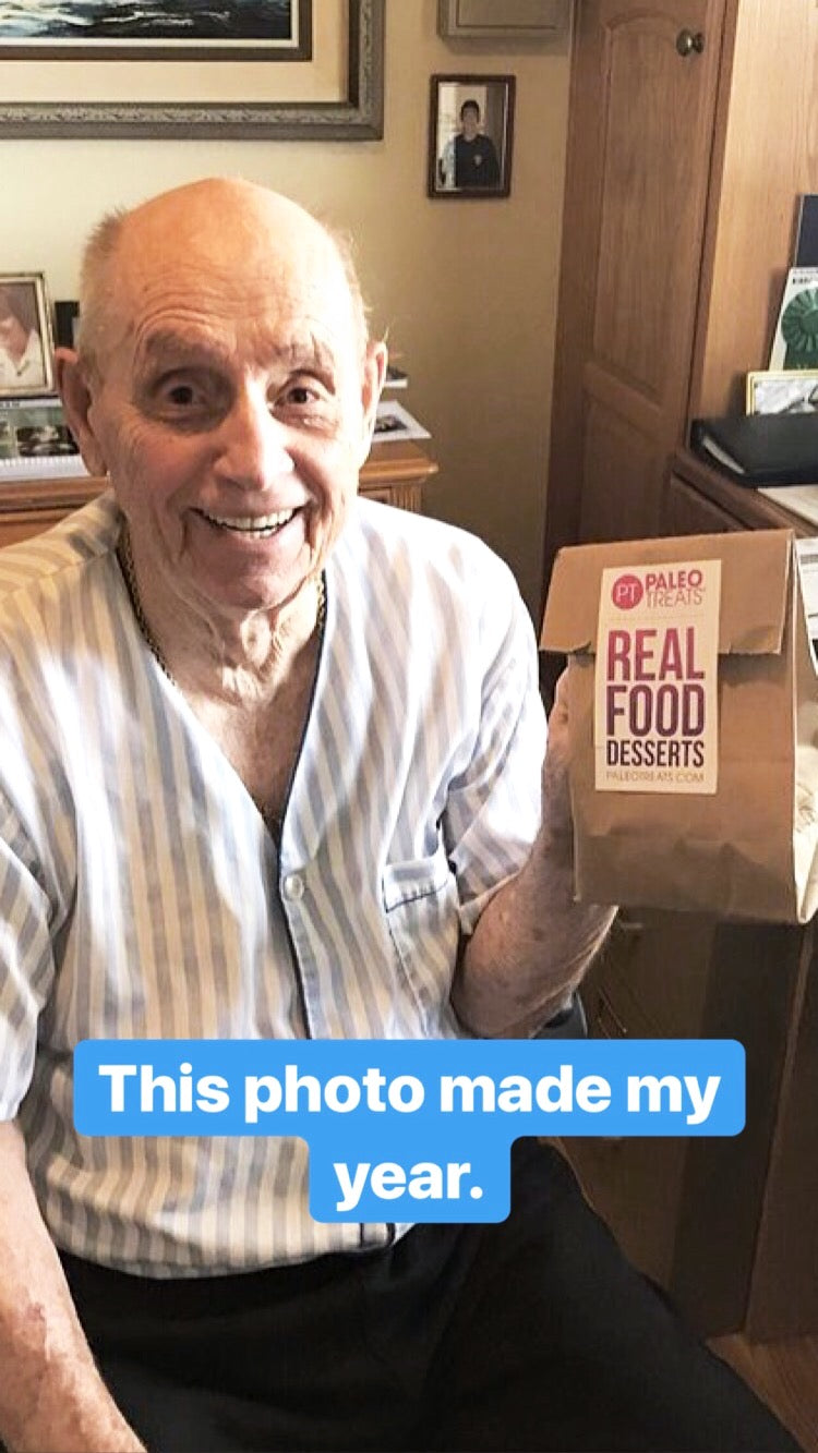 Older man holding up sampler bag of paleo desserts.