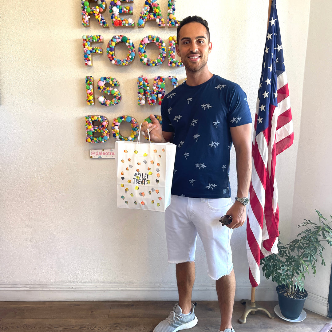 Small stack sampler smiling man holds bag of paleo treats in store on adams ave in san diego.