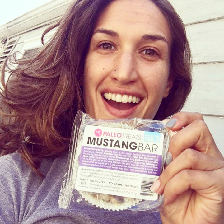 Smiling woman holding paleo treats mustang bar a paleo granola bar.