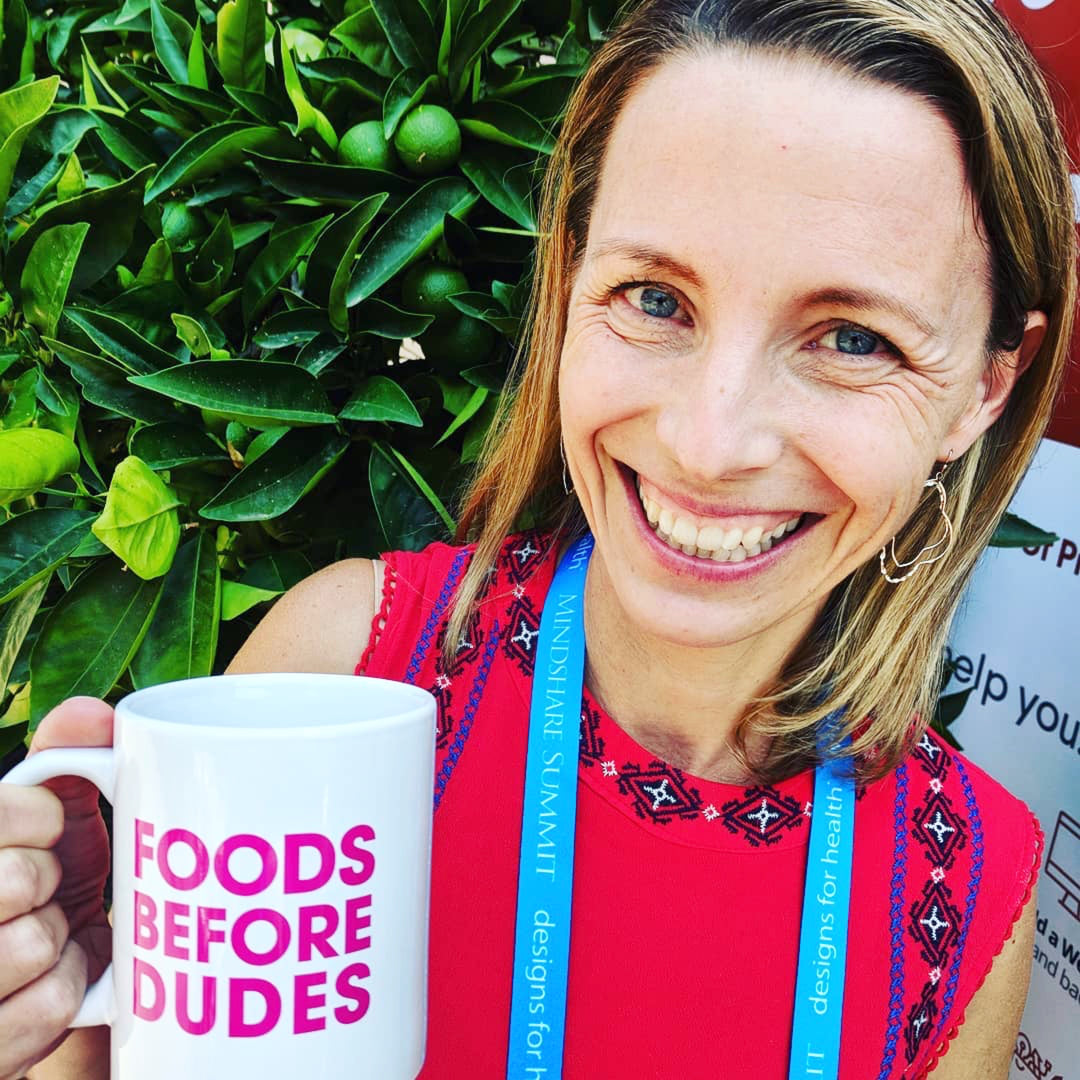 Smiling woman with foods before dudes coffee mug.