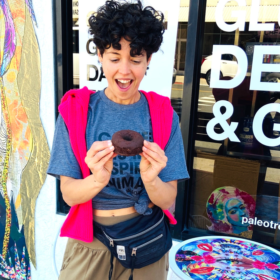 Woman smiling at a chocolate protein keto donut.