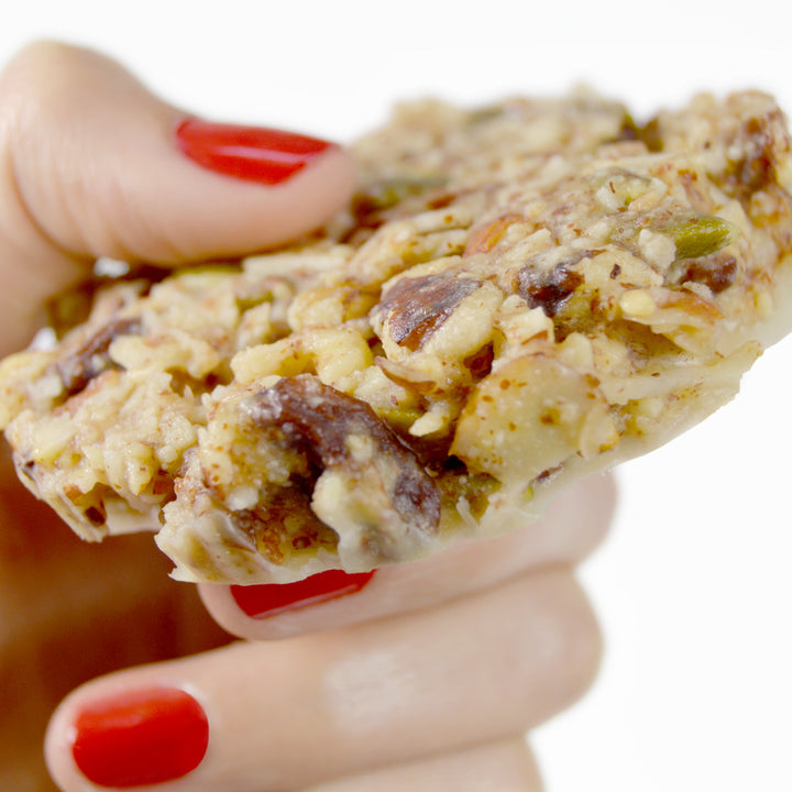 Womans hand holding mustang bar a paleo oatmeal raisin cookie granola bar by paleo treats.